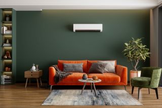 Air conditioner on a wall above a sofa in a green living room